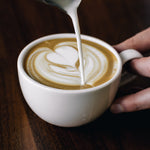 Milchschaum wird in Cappuccino gegossen, um ein Herzmuster zu formen – Latte-Art-Kurs in Hamburg