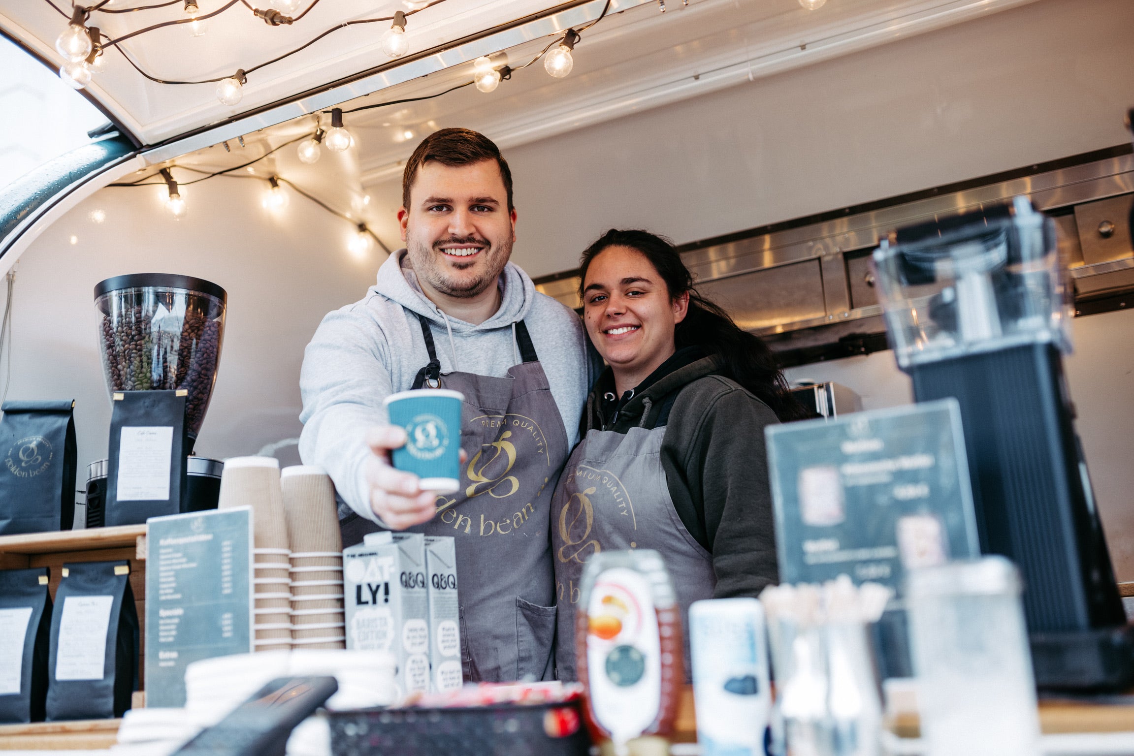 Golden Bean Barista serviert Kaffee in einem mobilen Kaffeewagen.