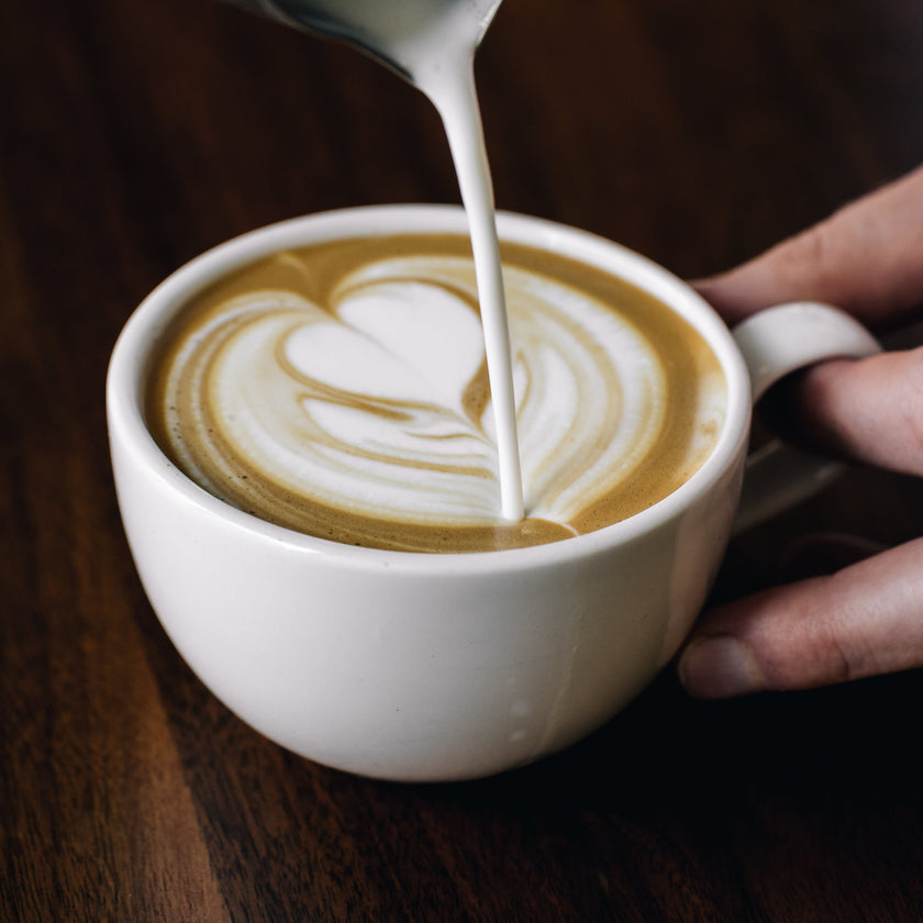 Milchschaum wird in Cappuccino gegossen, um ein Herzmuster zu formen – Latte-Art-Kurs in Hamburg